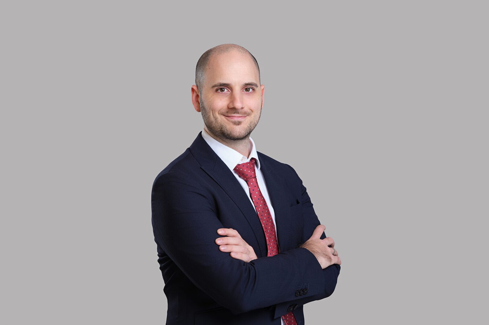Arcmont — Team portrait in a navy suit and red tie, grey background